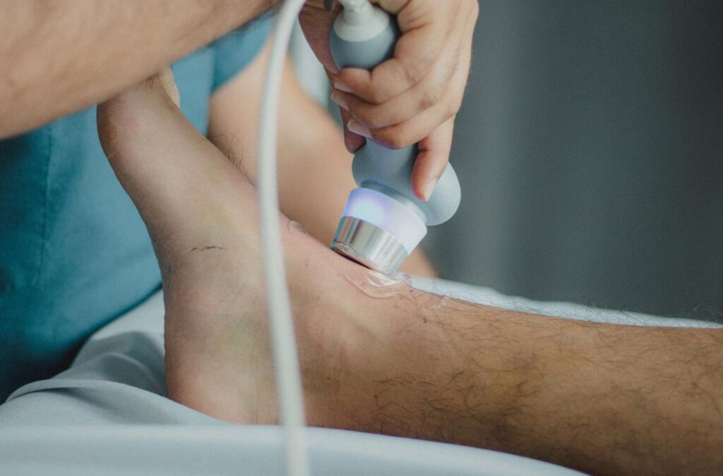Głowica do ultradźwięków z żelem prowadzona po odsłoniętym kolanie podczas zabiegu fizykoterapii